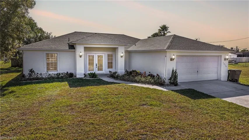 Ranch-style house featuring stucco siding, french doors, roof with shingles, and a yard