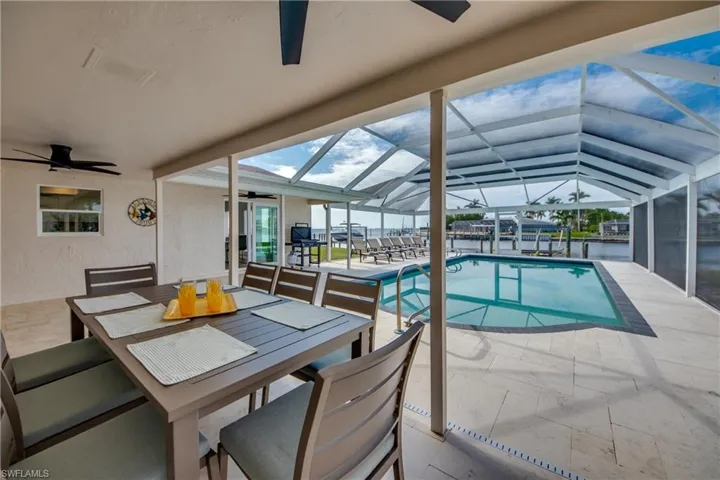 Swimming pool with a ceiling fan, a patio area, outdoor dining area, and a lanai
