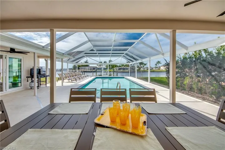 Outdoor pool featuring ceiling fan, a water view, a patio, and a lanai