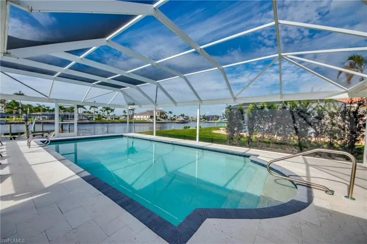 Outdoor pool featuring a water view, glass enclosure, and a patio