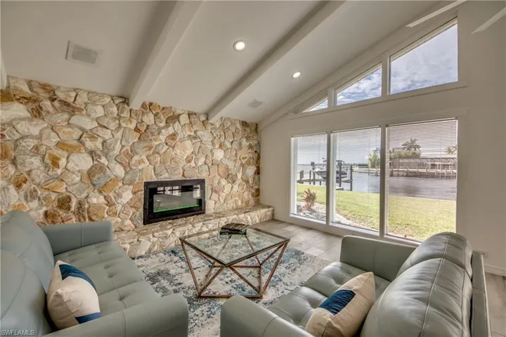 Living room with a water view, wood finished floors, recessed lighting, and a stone fireplace