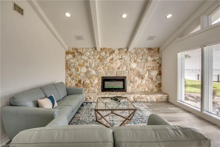 Living area with healthy amount of natural light, wood finished floors, beam ceiling, a fireplace, and recessed lighting