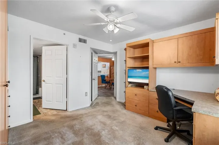 Carpeted home office featuring ceiling fan
