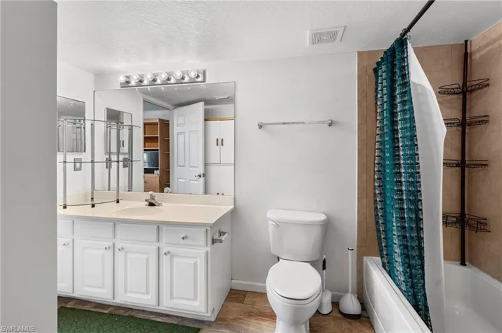 Full bathroom featuring shower / bath combo, vanity, a textured ceiling, and toilet