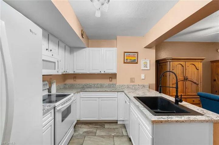 Kitchen with white cabinetry, sink, white appliances, and kitchen peninsula
