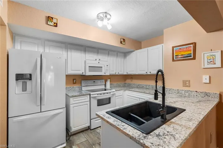 Kitchen with sink, white cabinets, white appliances, and kitchen peninsula