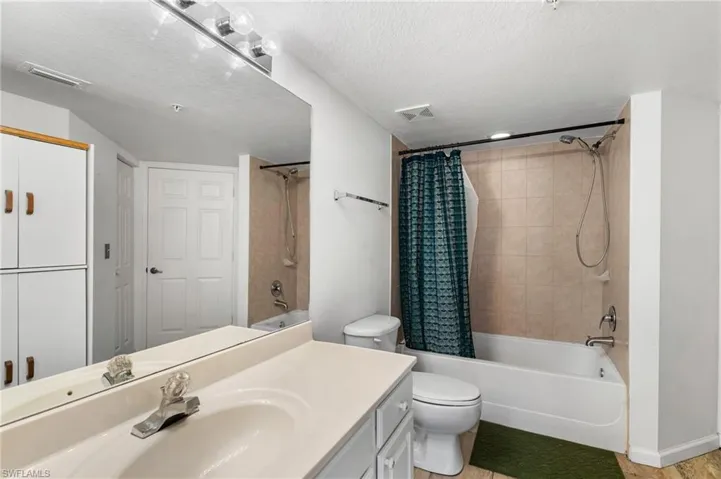 Full bathroom with vanity, toilet, a textured ceiling, and shower / bath combo with shower curtain