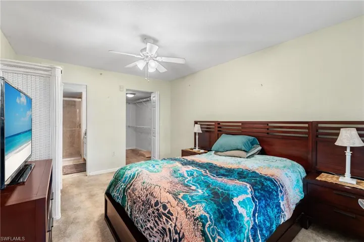 Bedroom with ceiling fan, ensuite bathroom, light carpet, a walk in closet, and a closet