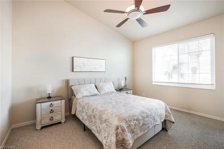 Carpeted bedroom featuring lofted ceiling and a ceiling fan