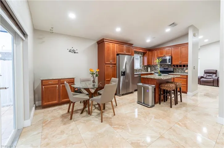 Kitchen featuring stainless steel appliances, tasteful backsplash, brown cabinets, lofted ceiling, and a kitchen island