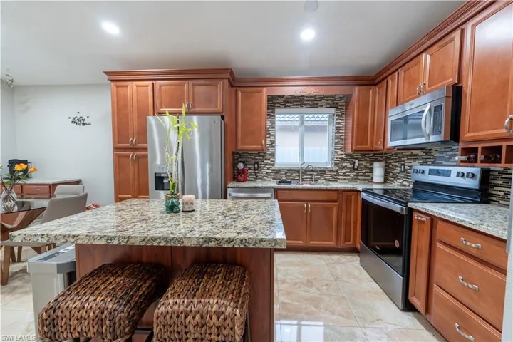 Kitchen with stainless steel appliances, backsplash, a breakfast bar, and brown cabinetry