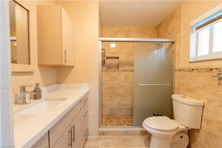 Full bath with vanity, a shower stall, tile walls, and tile patterned floors
