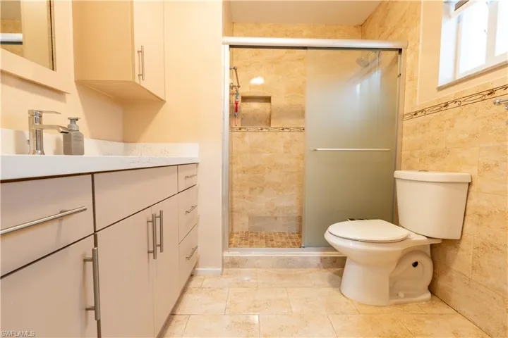 Bathroom featuring vanity, a shower stall, and tile walls