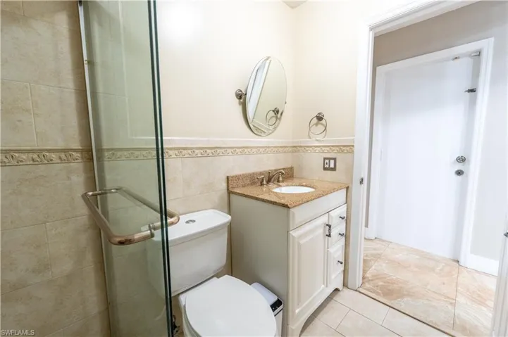 Bathroom featuring vanity, a stall shower, wainscoting, tile walls, and tile patterned flooring