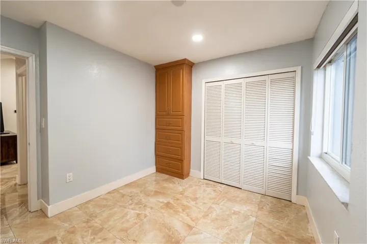 Unfurnished bedroom featuring a closet, multiple windows, light marble finish flooring, and recessed lighting
