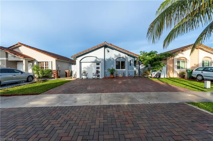 Mediterranean / spanish home featuring stucco siding, a tile roof, decorative driveway, and a front lawn