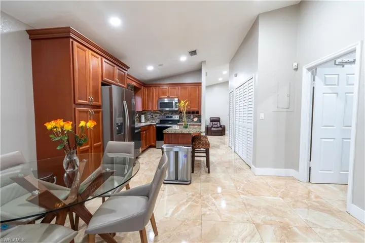 Kitchen with lofted ceiling, decorative backsplash, appliances with stainless steel finishes, a breakfast bar area, and recessed lighting