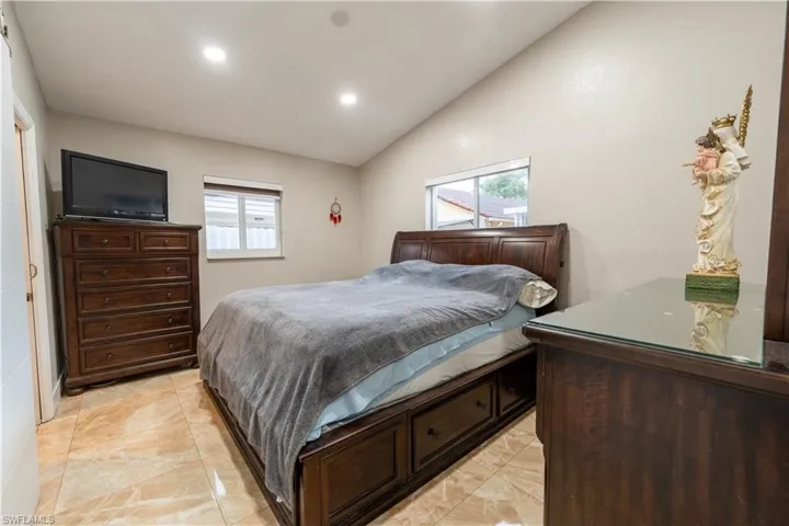Bedroom with vaulted ceiling, recessed lighting, and light marble finish flooring