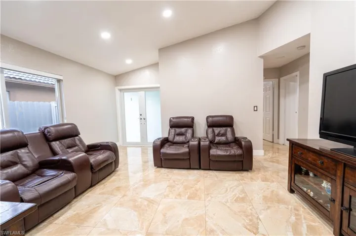 Cinema with vaulted ceiling, recessed lighting, and light marble finish floors