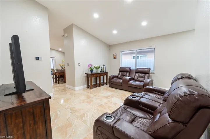 Living area with recessed lighting, light marble finish floors, and lofted ceiling