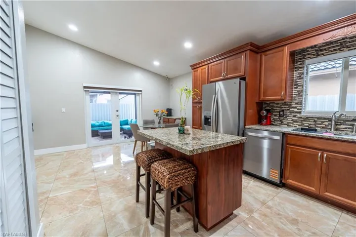 Kitchen with healthy amount of natural light, appliances with stainless steel finishes, vaulted ceiling, backsplash, and a kitchen island