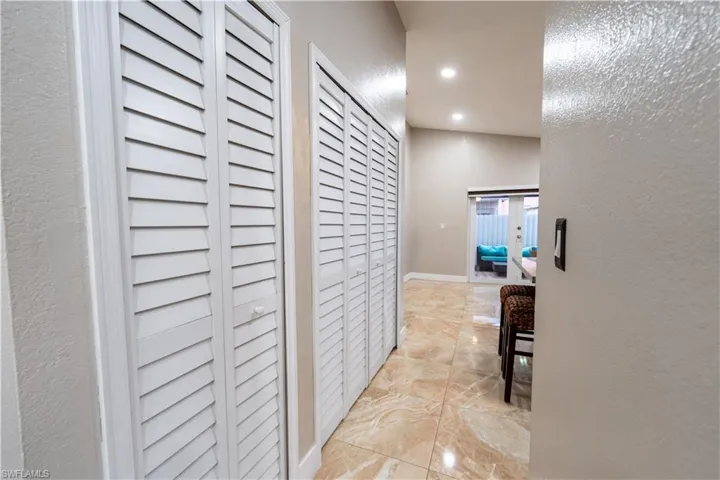 Hallway with light marble finish flooring, recessed lighting, and a textured wall