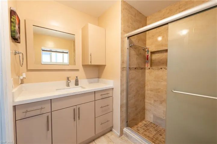 Full bathroom with vanity, a shower stall, and tile patterned flooring