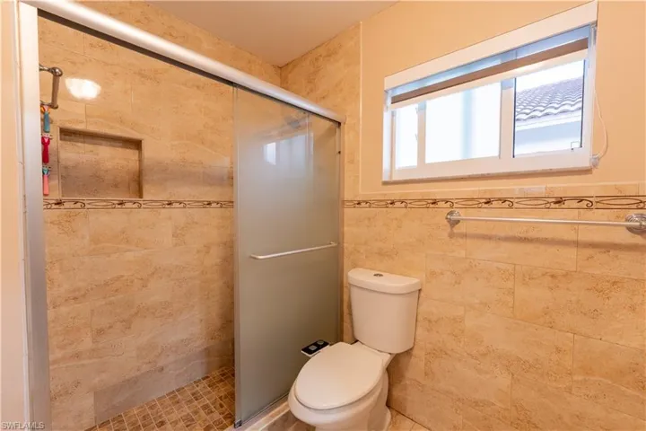 Full bath with a shower stall and tile walls