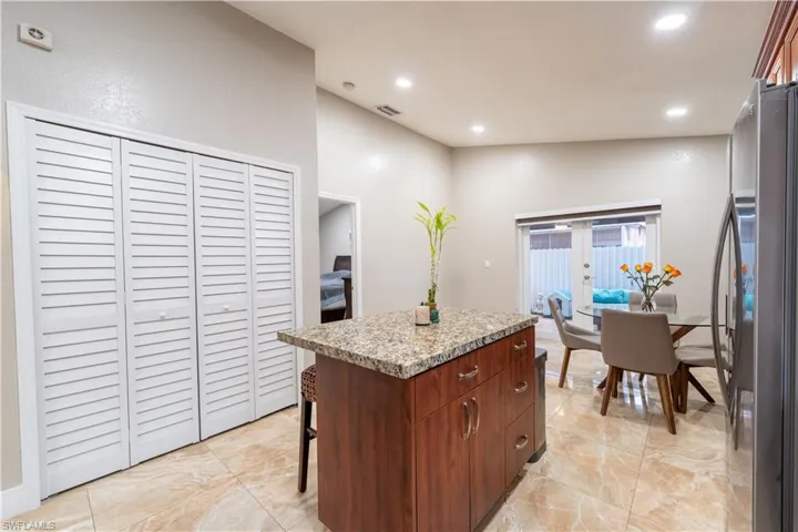 Kitchen with french doors, light marble finish floors, freestanding refrigerator, a kitchen island, and recessed lighting