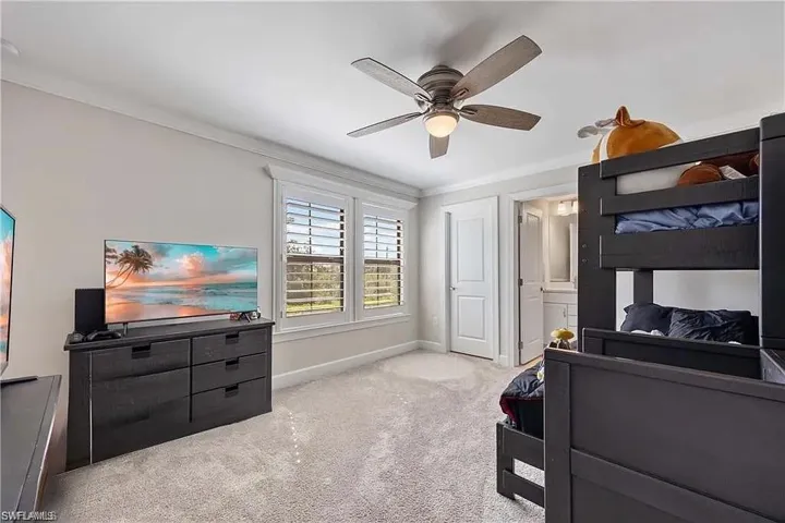 Carpeted bedroom featuring baseboards, crown molding, and a ceiling fan