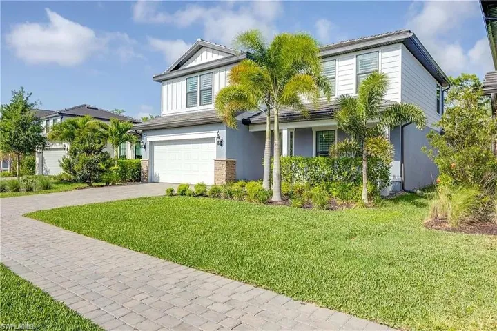 Traditional-style home with driveway, an attached garage, a front yard, and stucco siding