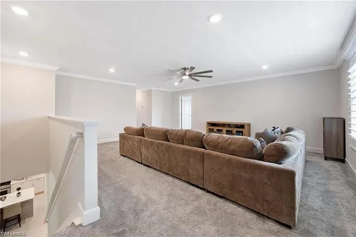 Carpeted living area with recessed lighting, baseboards, a ceiling fan, and crown molding