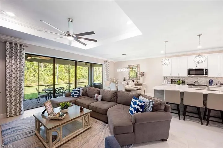 Living area with ceiling fan, plenty of natural light, a tray ceiling, ornamental molding, and recessed lighting