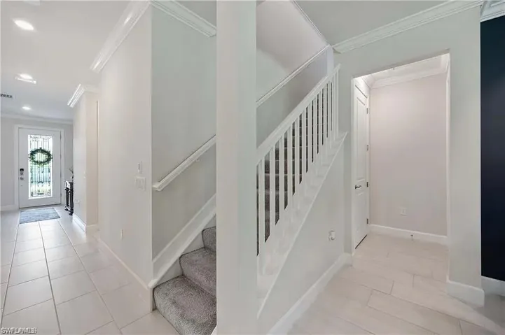 Staircase with ornamental molding, recessed lighting, baseboards, and tile patterned floors