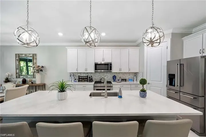 Kitchen with appliances with stainless steel finishes, a chandelier, tasteful backsplash, light countertops, and crown molding