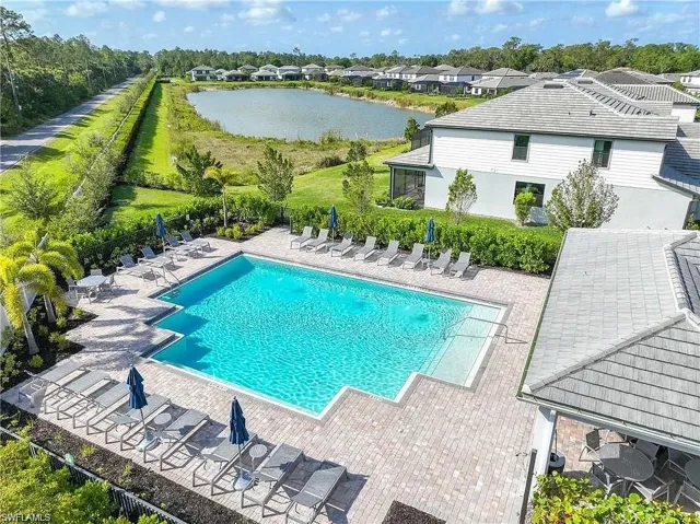Community pool with a water view, a patio, fence, and a residential view