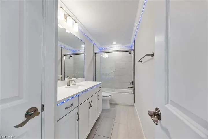 Full bathroom with vanity, tile patterned floors, crown molding, toilet, and baseboards