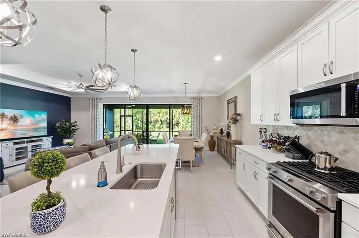 Kitchen with stainless steel appliances, a sink, open floor plan, backsplash, and light countertops