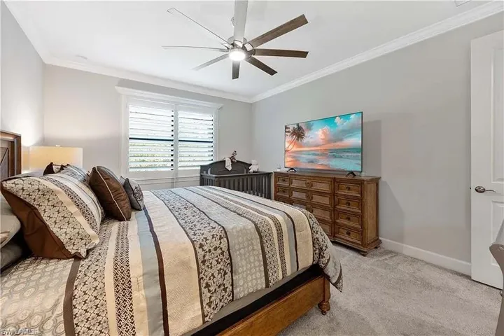 Bedroom with crown molding, light colored carpet, baseboards, and a ceiling fan