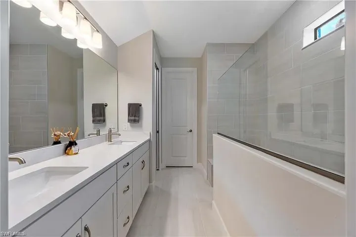 Full bath with a tile shower and double vanity