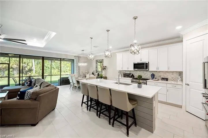 Kitchen featuring appliances with stainless steel finishes, open floor plan, a sink, a kitchen breakfast bar, and ornamental molding