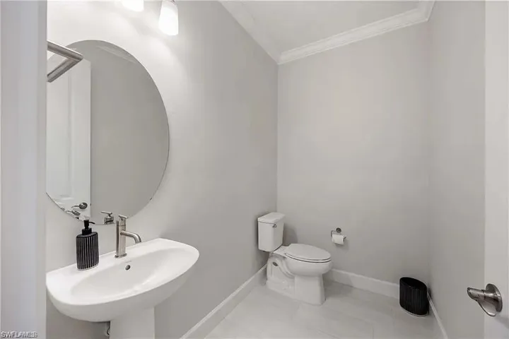 Bathroom with crown molding, baseboards, toilet, a sink, and tile patterned flooring
