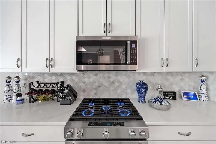 Kitchen featuring stainless steel appliances, light countertops, and white cabinets