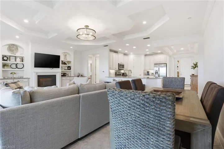 Living room with built in shelves, a chandelier, a fireplace, recessed lighting, and ornamental molding