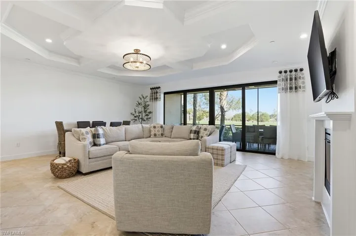 Living area featuring coffered ceiling, a chandelier, beamed ceiling, a fireplace, and light tile patterned floors