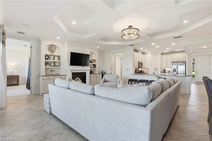 Living area featuring built in features, a chandelier, light tile patterned floors, a fireplace, and ornamental molding