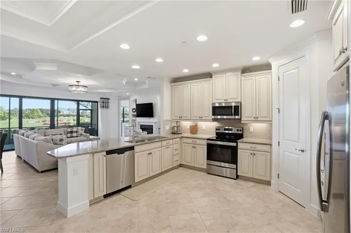 Kitchen featuring open floor plan, a peninsula, stainless steel appliances, recessed lighting, and light stone countertops