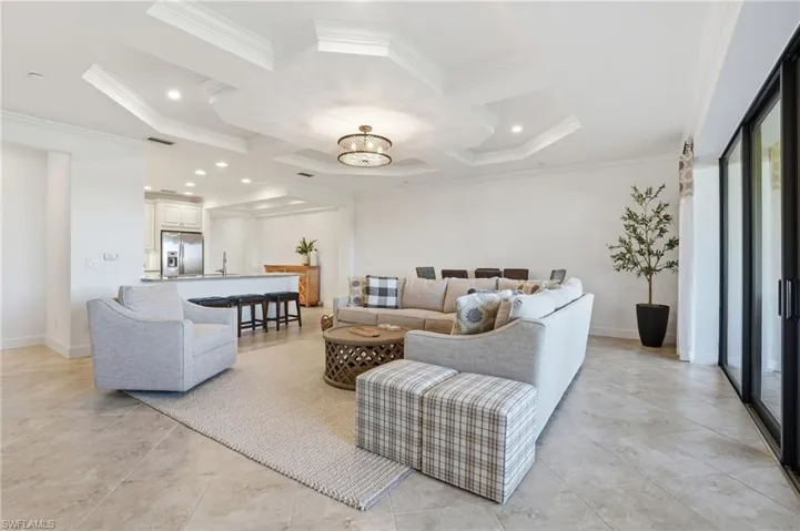 Living room with coffered ceiling, a chandelier, beamed ceiling, ornamental molding, and recessed lighting