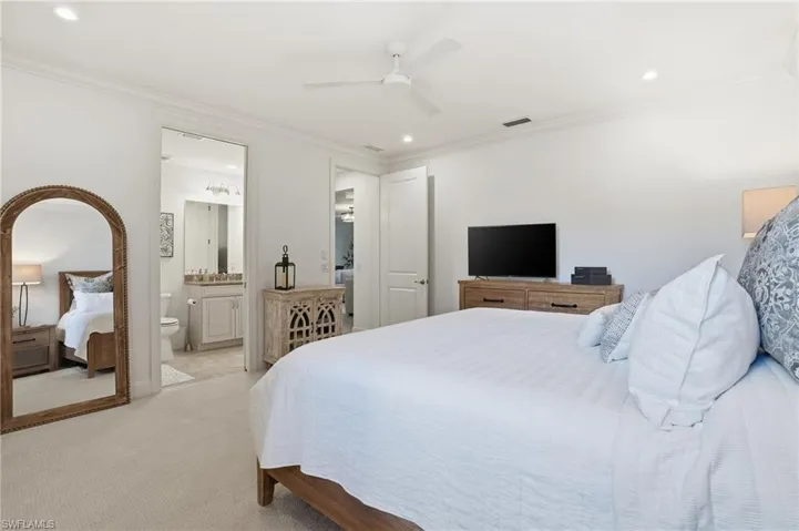Carpeted bedroom with recessed lighting, crown molding, ceiling fan, and ensuite bath