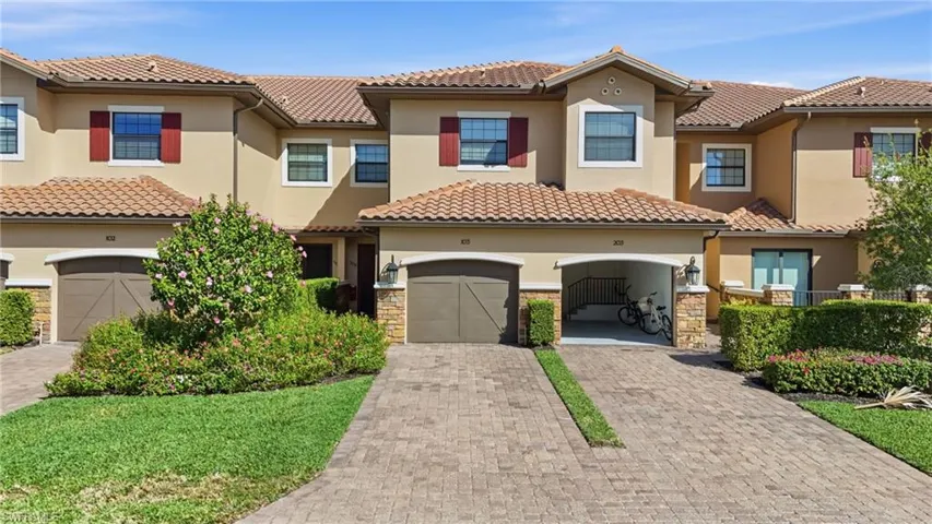 Mediterranean / spanish-style house with driveway, stucco siding, stone siding, a tile roof, and an attached garage